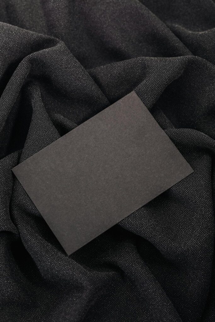 Black card on textured black fabric background, ideal for mockups and design presentations.